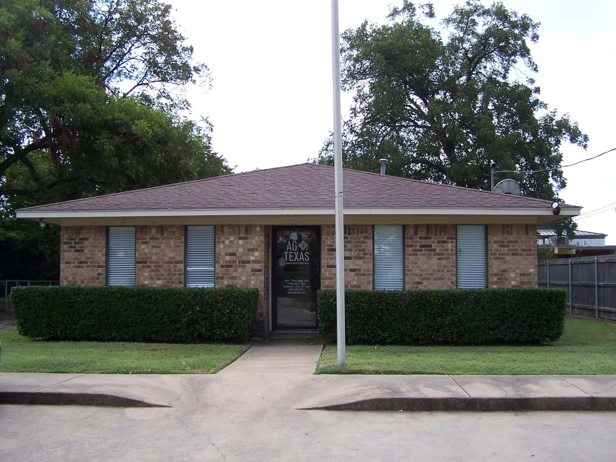 Single-story brick office with manicured bushes in Hillsboro, Texas.