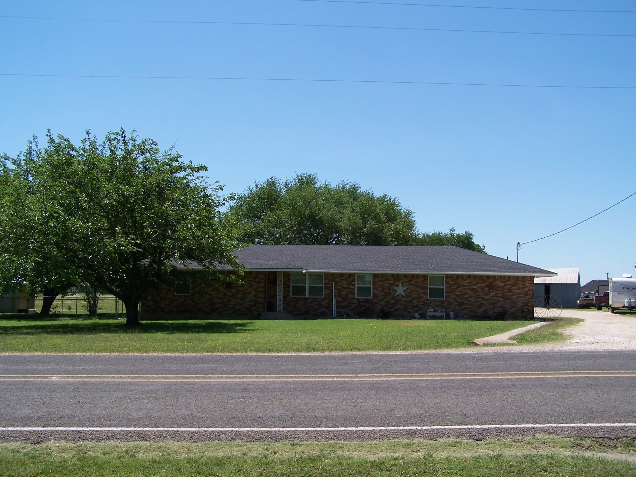 Brick house with front yard and trees in Hillsboro, West Hill County, McLennan County.