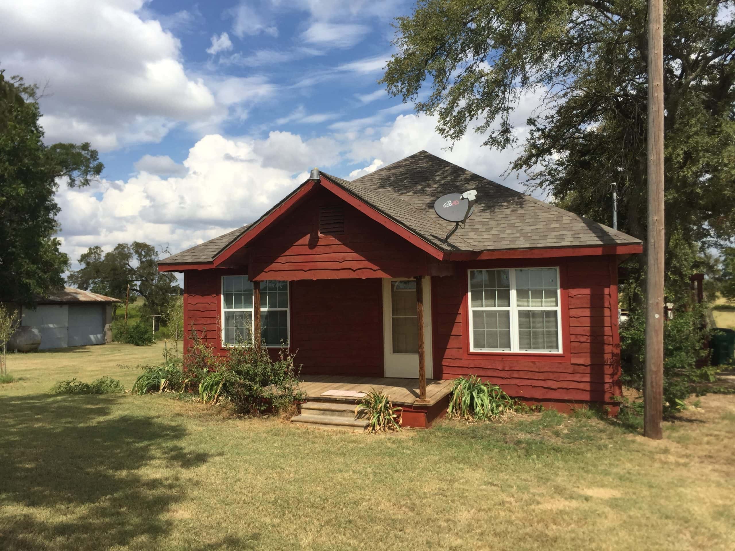 Red house with front porch and large windows in Hillsboro, Texas.