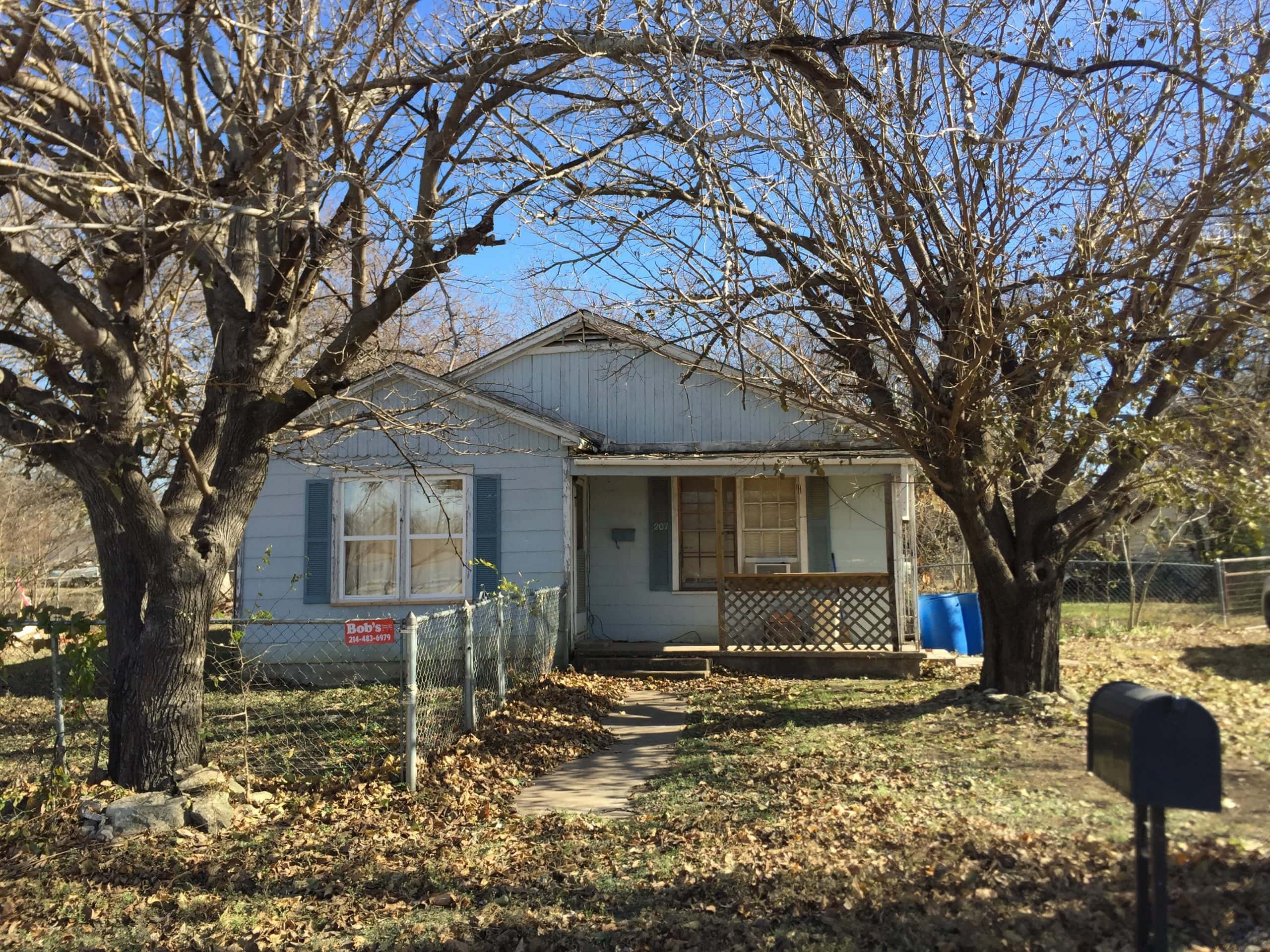 Old house with large trees and a cozy porch in Hillsboro, West, Texas.