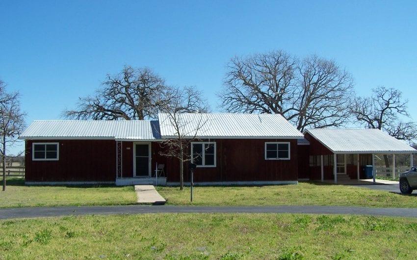 House with metal roof and front yard in Abbott, West Hillsboro, McLennan County.