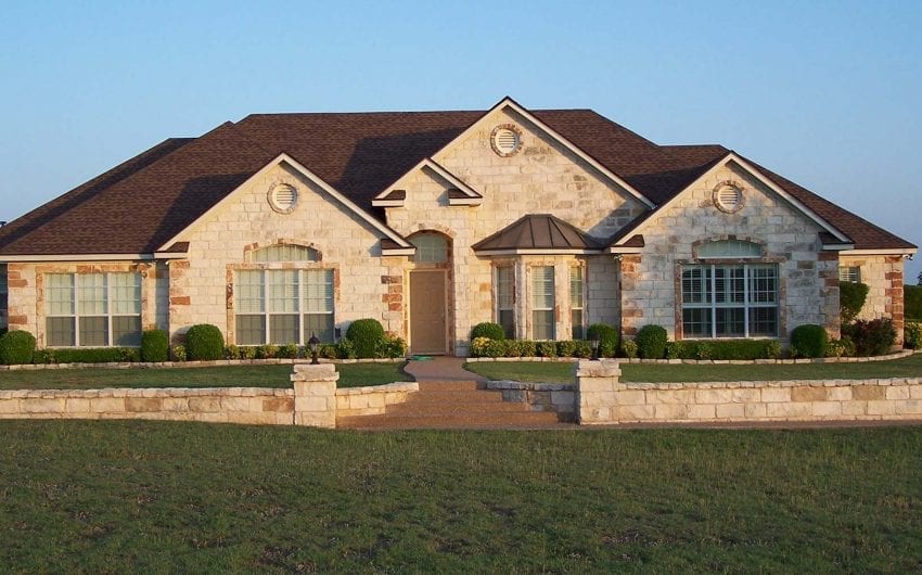 Abbott, TX house with stone facade, large windows, and well-maintained lawn.